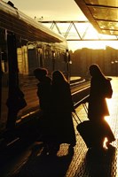 Silhouetted women boarding train with baggage