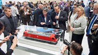 Crowd of people looking at train model at conference