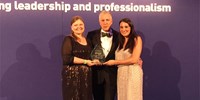 Three people posing for photo with award