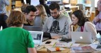 Four people sitting at a table with laptop computers