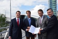 Four men posing for photo with contract