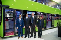 Four men in suit posing for photo in front of green bus