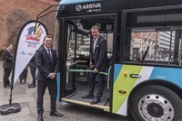 Two men cutting ribbon on a bus