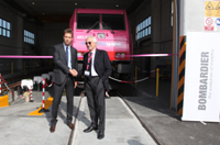 Two men shaking hands in front of train