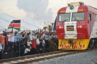 People celebrating next to red train in Kenya