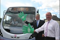 Men with giant, green, foam hands, in front of bus
