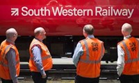 Workers standing next to red South Western Railway train