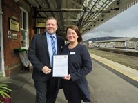 Man and woman holding certification on train platform