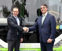 Two men shaking hands in front of bus