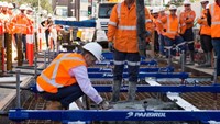 Man in fluro spreading concrete on light rail construction