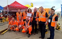 Workers in orange holding award