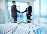 Two people shaking hands, documents in forground